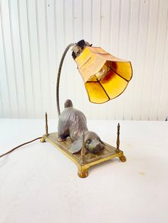 a lamp that is sitting on top of a wooden base with a bird figurine underneath it