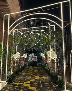 an archway decorated with lights and hanging ornaments in the middle of a walkway at night