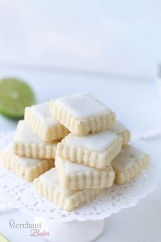 small cookies are stacked on a white doily with limes in the back ground