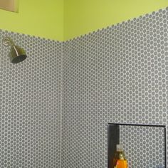 a bathroom with green walls and white polka dots on the wall, along with a shower head