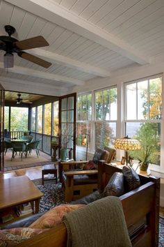 a living room filled with lots of furniture next to a large glass wall window and ceiling fan