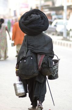 a person walking down the street with a bucket and some kind of bag on his back