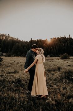 a man and woman are holding hands in the grass with trees in the back ground