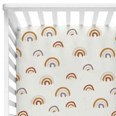 a white crib bed with rainbows on the sheets and bottom sheet in gold