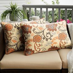 two pillows sitting on top of a couch next to a potted plant