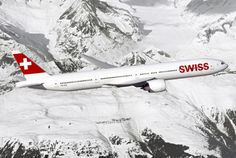 an airplane is flying in the sky over snow covered mountains and trees with swiss letters on it