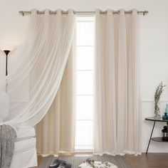 a living room filled with furniture and a window covered in white drapes next to a wooden floor