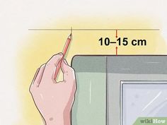 a hand holding a pencil near a drawing board with measurements for the area in front of it