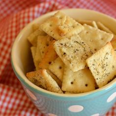 a blue bowl filled with crackers on top of a red and white checkered table cloth