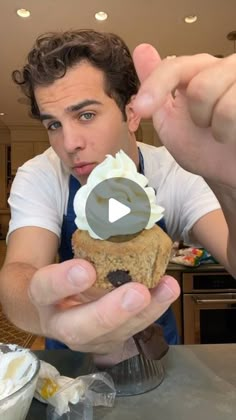 a man holding up a cupcake with frosting on it in front of his face