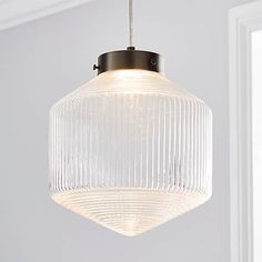 a glass light hanging from a ceiling fixture in a room with white walls and windows