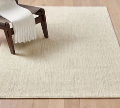 a chair sitting on top of a wooden floor next to a white rug with fringes