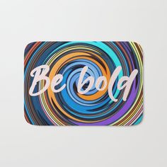 a bath mat with the words be bold in white letters on it, surrounded by multicolored swirls