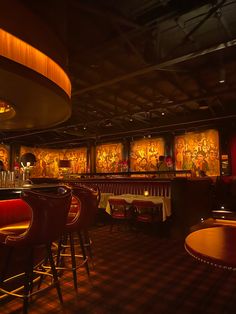 a dimly lit restaurant with many tables and stools in front of the bar area