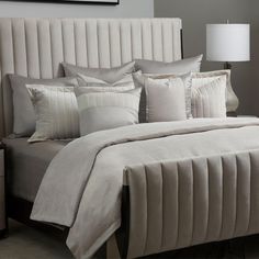 a bed with white sheets and pillows in a bedroom