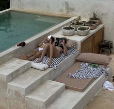 two women lounging on loungers next to a swimming pool