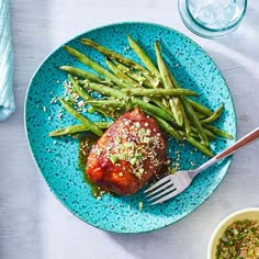 a blue plate topped with meat and green beans