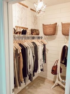 an open closet with clothes hanging on rails and baskets in the corner next to it