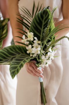 a bride holding a bouquet of flowers and greenery