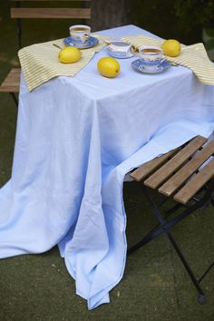 the table is set with two lemons and plates on it, along with an empty wooden bench