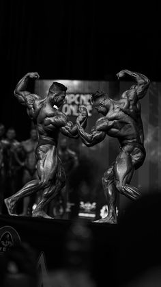 two bodybuilding competitors flexing their muscles on stage