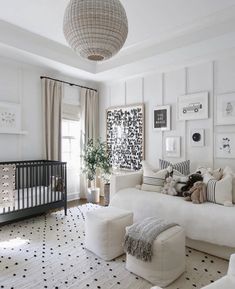 a living room with white furniture and black and white decor on the walls, along with a baby's crib