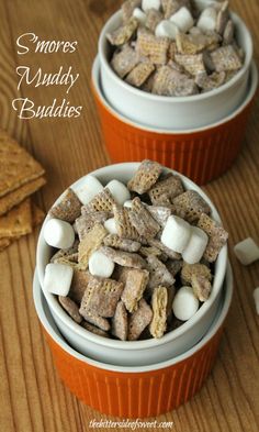 two orange cups filled with marshmallows on top of a wooden table next to crackers