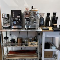 an espresso machine sitting on top of a metal shelf next to other coffee machines