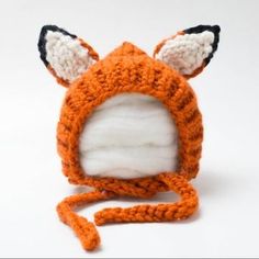 a crocheted hat with ears and tail is made to look like a fox