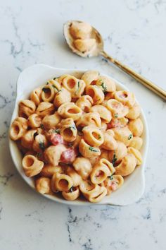 a white bowl filled with macaroni and cheese on top of a marble counter