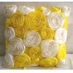 a yellow and white pillow with rolled flowers on it