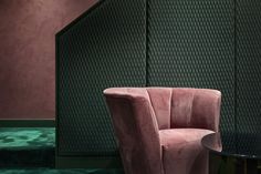 a pink chair next to a black table in a room with green carpet and walls