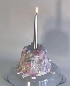 a candle that is sitting on top of a glass cake plate with an angel decoration