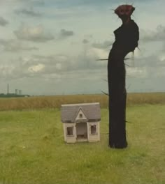 a house in the middle of a field with a creepy figure standing next to it