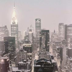 the city skyline is lit up at night with snow on the ground and skyscrapers in the background