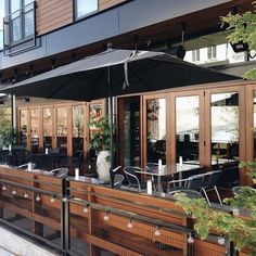 an outdoor dining area with tables and umbrellas on the side of the street in front of a building