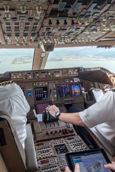 two pilots are sitting in the cockpit of an airplane and looking at their ipads