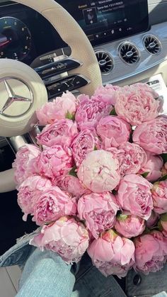 a bouquet of pink peonies sitting in the drivers seat of a car