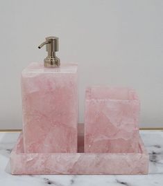 a pink marble soap dispenser and holder on a white marble countertop