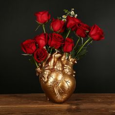 a vase filled with red roses on top of a wooden table