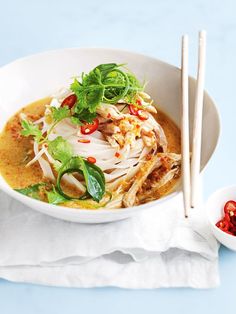 a white bowl filled with soup next to two chopsticks on top of a napkin