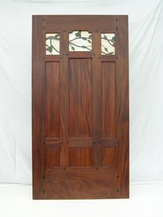 a wooden door with stained glass panels on the top and bottom panel, in front of a white backdrop