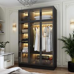 an open closet with clothes hanging on the doors and lights above it, in a white room