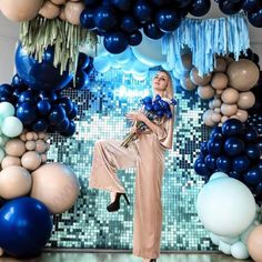 a woman standing in front of balloons and streamers