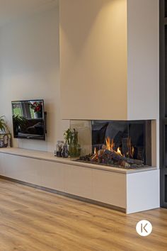 a living room with a fire place and television on the wall, in front of a large window