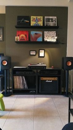 a room with some speakers and pictures on the wall above it in front of a stereo system