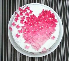 a white plate topped with a heart shaped cake covered in pink butterfly confetti