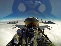 a fighter jet flying through the sky next to another plane in front of it's cockpit