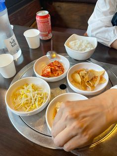 a person sitting at a table with bowls of food in front of them on a tray