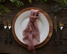 a white plate topped with a pink napkin next to silverware and utensils